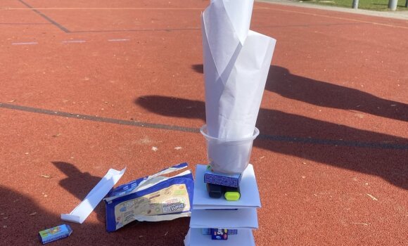 Zu sehen ist ein Turm, der aus verschiedenen Materialien zusammengebaut wurde. In diesem Fall hauptsächlich aus Papier und Smartieboxen..