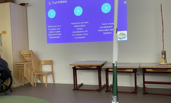 Zu sehen ist ein Turm, der aus verschiedenen Materialien zusammengebaut wurde. In diesem Fall hauptsächlich Dosen und Papier.