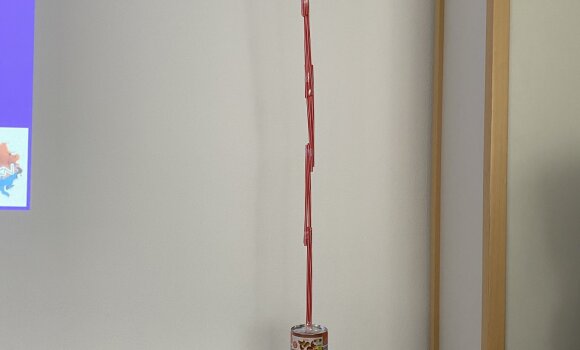 Zu sehen ist ein Turm, der aus verschiedenen Materialien zusammengebaut wurde. In diesem Fall hauptsächlich Strohhalme.