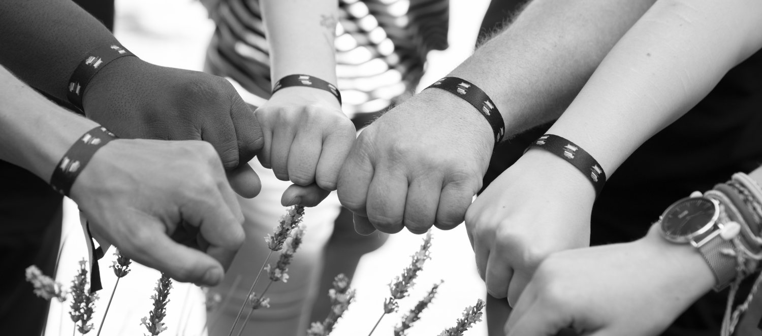 Halbkreis mit geschlossenen Fäusten und LHR Festivalband am Handgelenk