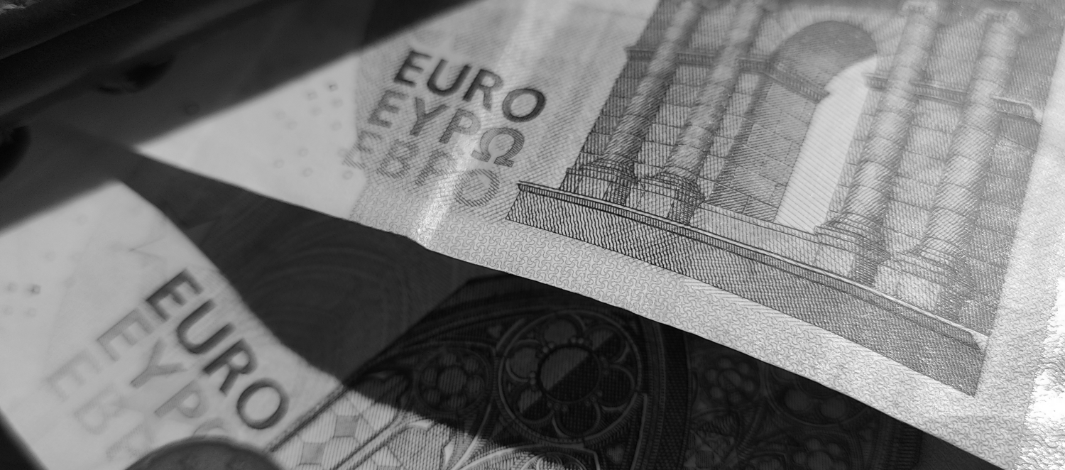 Zu sehen ist ein Portemonai aus dem ein 20€ und ein 5€ Schein herausguckt. 